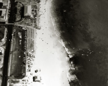 Looking over the car park and lawn terraces. The jetty has been demolished and the Cottesloe Surf Life Saving boatshed is still at the northern end of the beach c1963